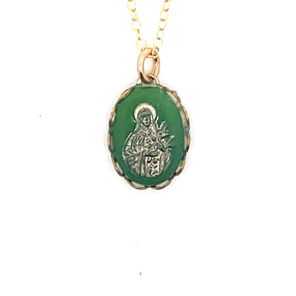 Detailed close-up of a vintage emerald green Virgin Mary cameo pendant with gold overlay showing the Madonna figure on a gold chain against a white background