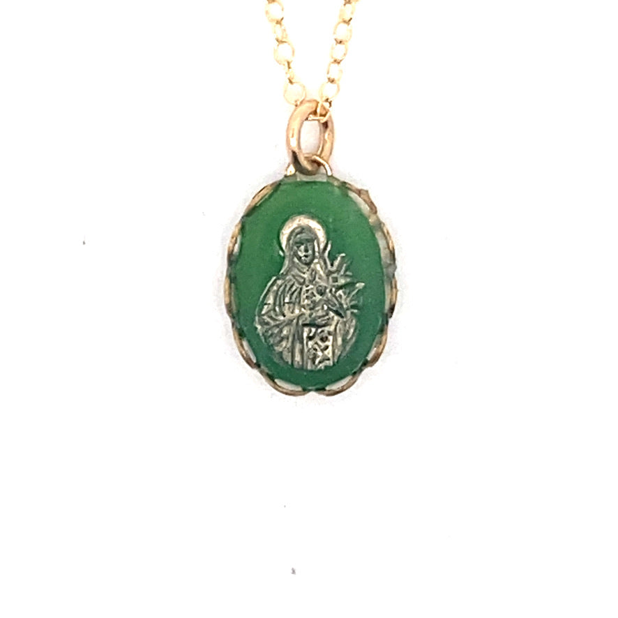 Detailed close-up of a vintage emerald green Virgin Mary cameo pendant with gold overlay showing the Madonna figure on a gold chain against a white background