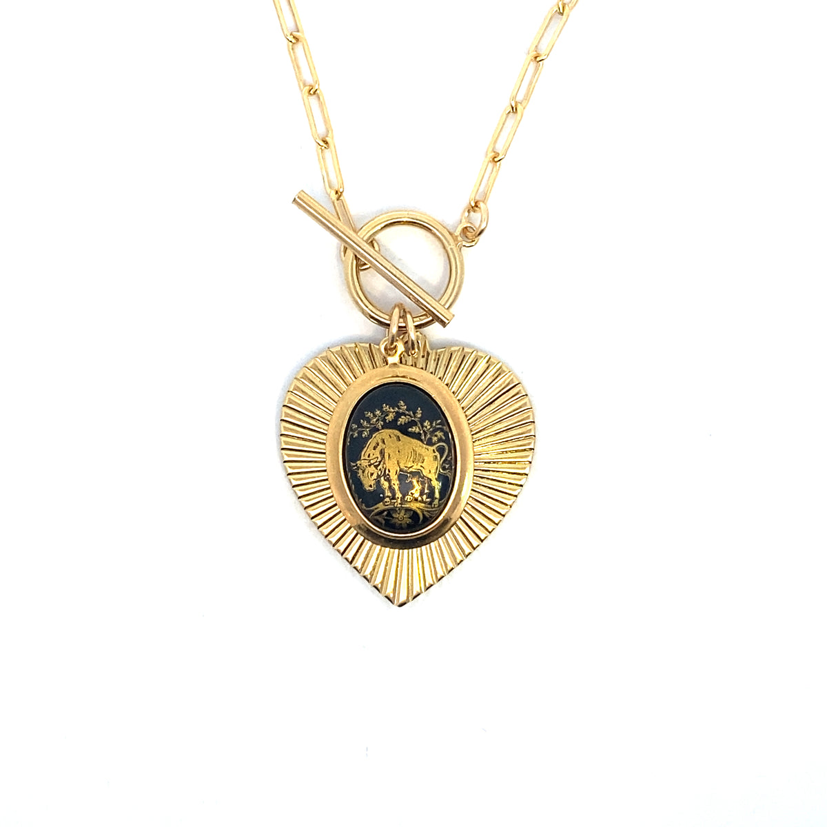 Gold heart-shaped sunburst pendant necklace on a paperclip chain with toggle clasp featuring a vintage German glass Taurus bull intaglio cameo in dark blue and gold on a white background
