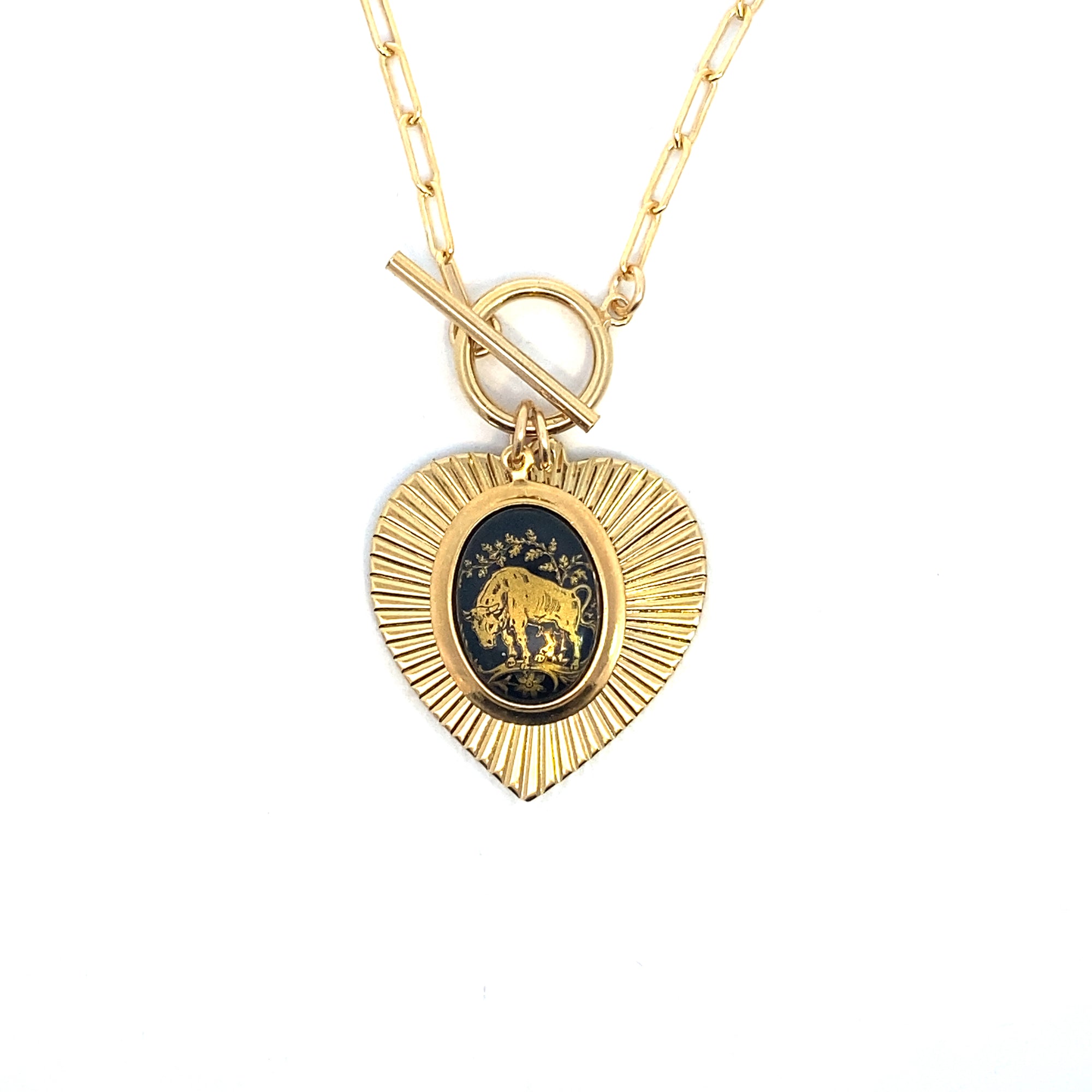 Gold heart-shaped sunburst pendant necklace on a paperclip chain with toggle clasp featuring a vintage German glass Taurus bull intaglio cameo in dark blue and gold on a white background