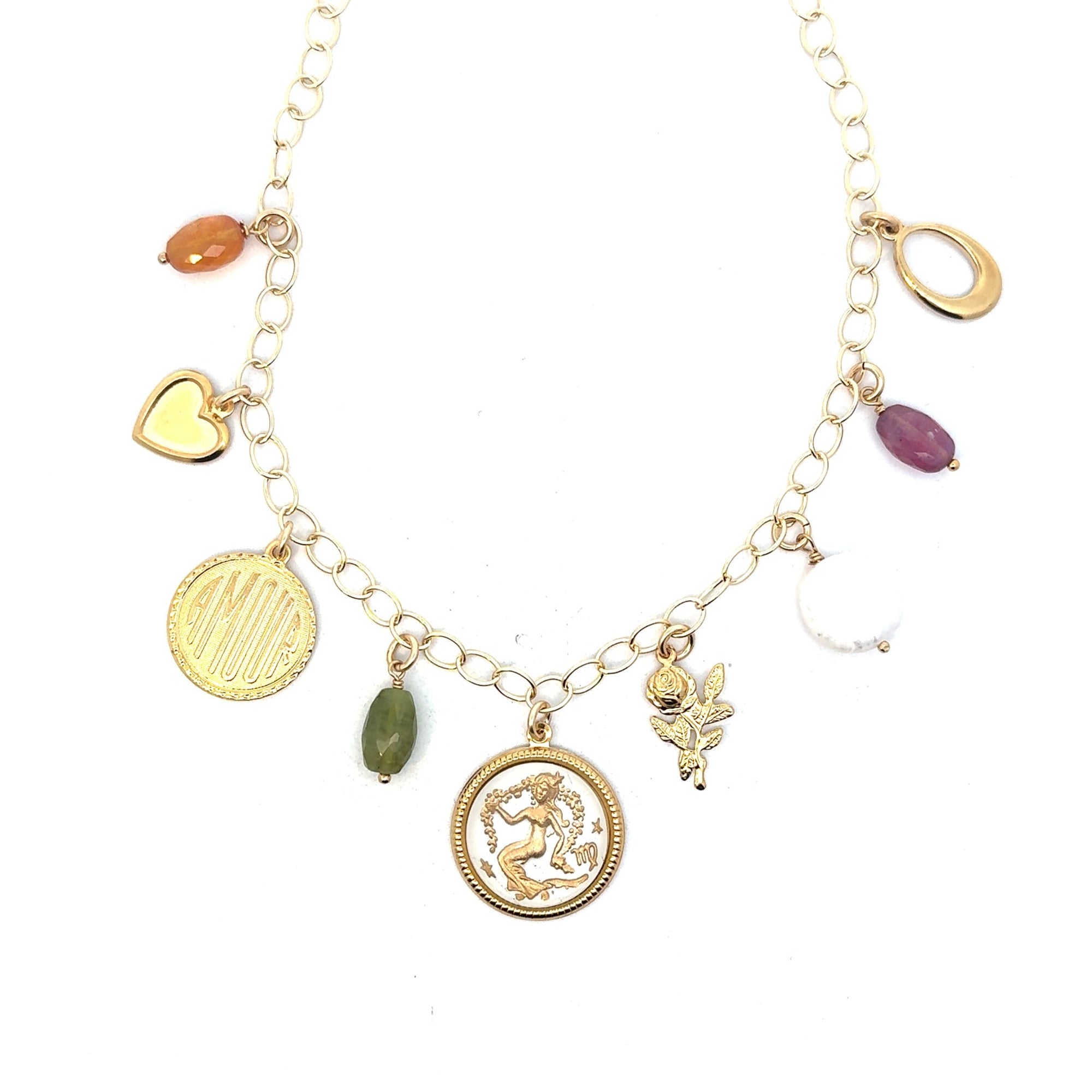 Gold charm necklace on a round link chain featuring a Virgo maiden zodiac coin pendant, Amour engraved disc, gold heart charm, rose charm, freshwater pearl, and orange carnelian, green jade, and purple gemstone beads on a white background