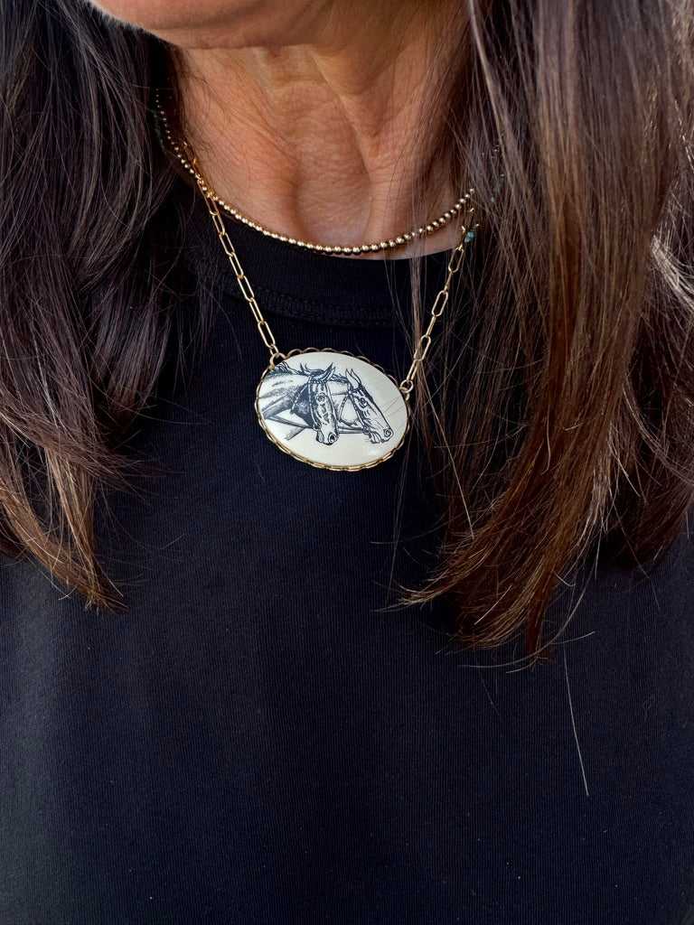 Necklace with a pendant featuring horse heads on a black background