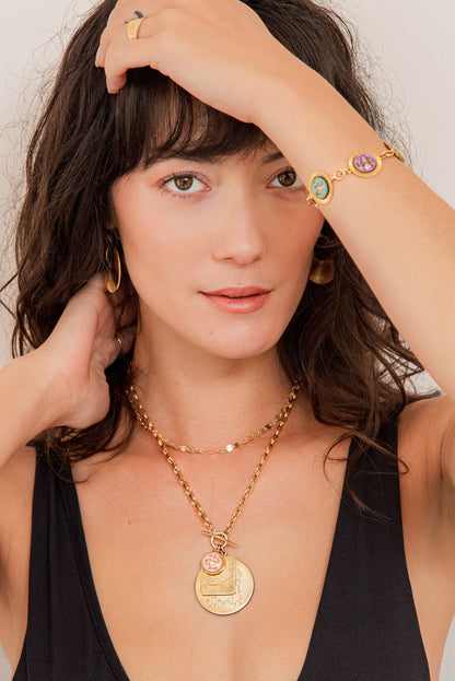 Woman wearing gold jewelry with a neutral background