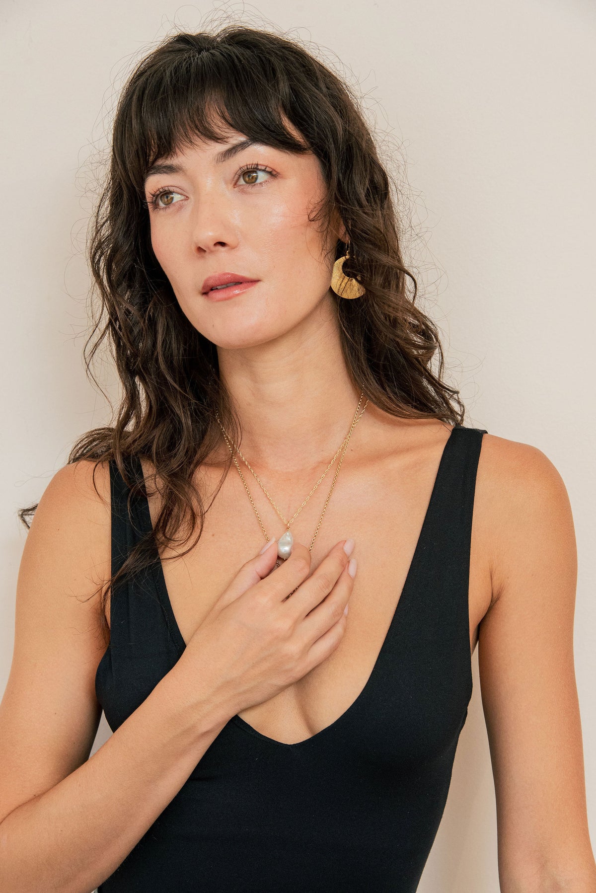 Woman wearing a black sleeveless top against a plain background