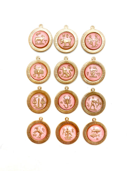 Collection of twelve gold round sunburst pendant charms with pink vintage glass zodiac intaglio cameos featuring all twelve zodiac signs arranged in a grid on a white background