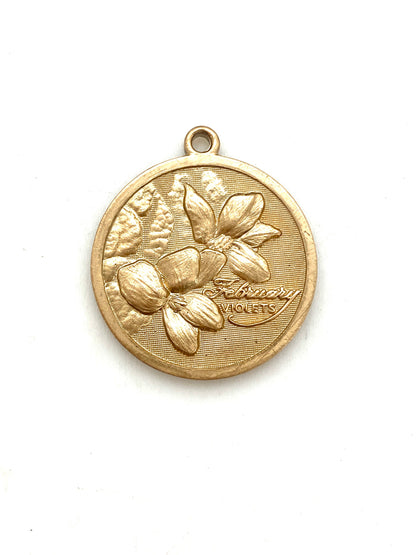 Gold embossed February violet birth month flower coin pendant charm on a white background