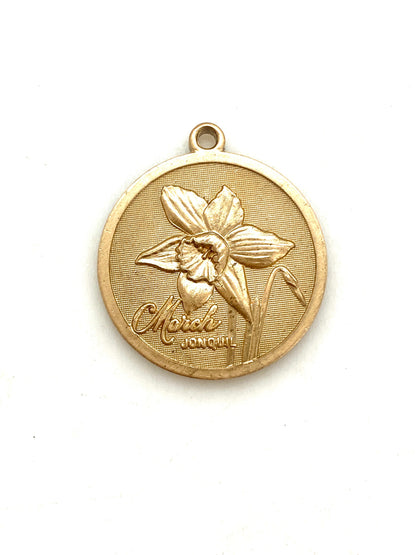 Gold embossed March jonquil birth month flower coin pendant charm on a white background