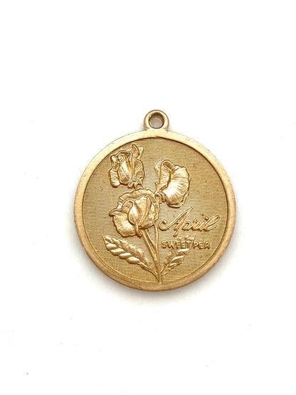 Gold embossed April sweet pea birth month flower coin pendant charm on a white background
