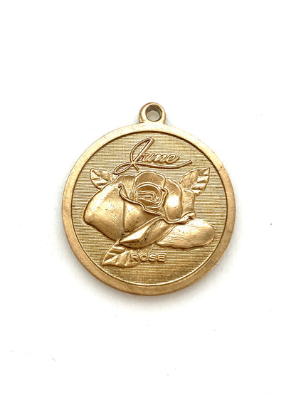 Gold embossed June rose birth month flower coin pendant charm on a white background