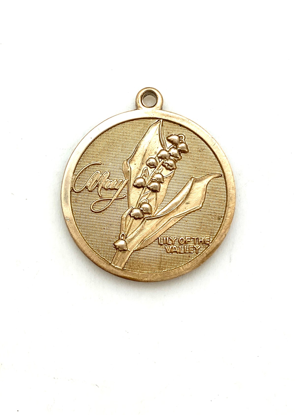 Gold embossed May lily of the valley birth month flower coin pendant charm on a white background