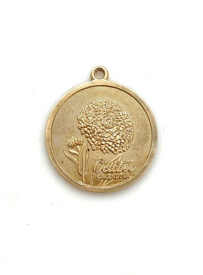 Gold embossed October calendula birth month flower coin pendant charm on a white background
