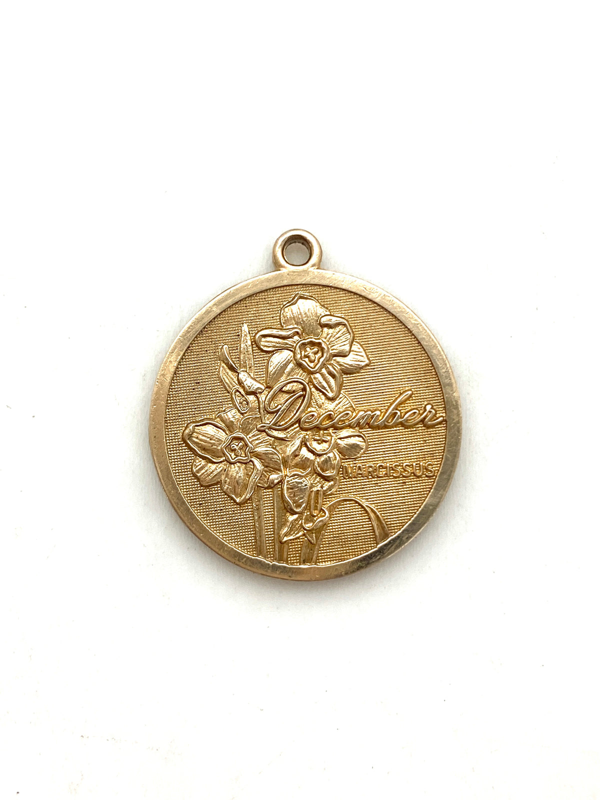 Gold embossed December narcissus birth month flower coin pendant charm on a white background
