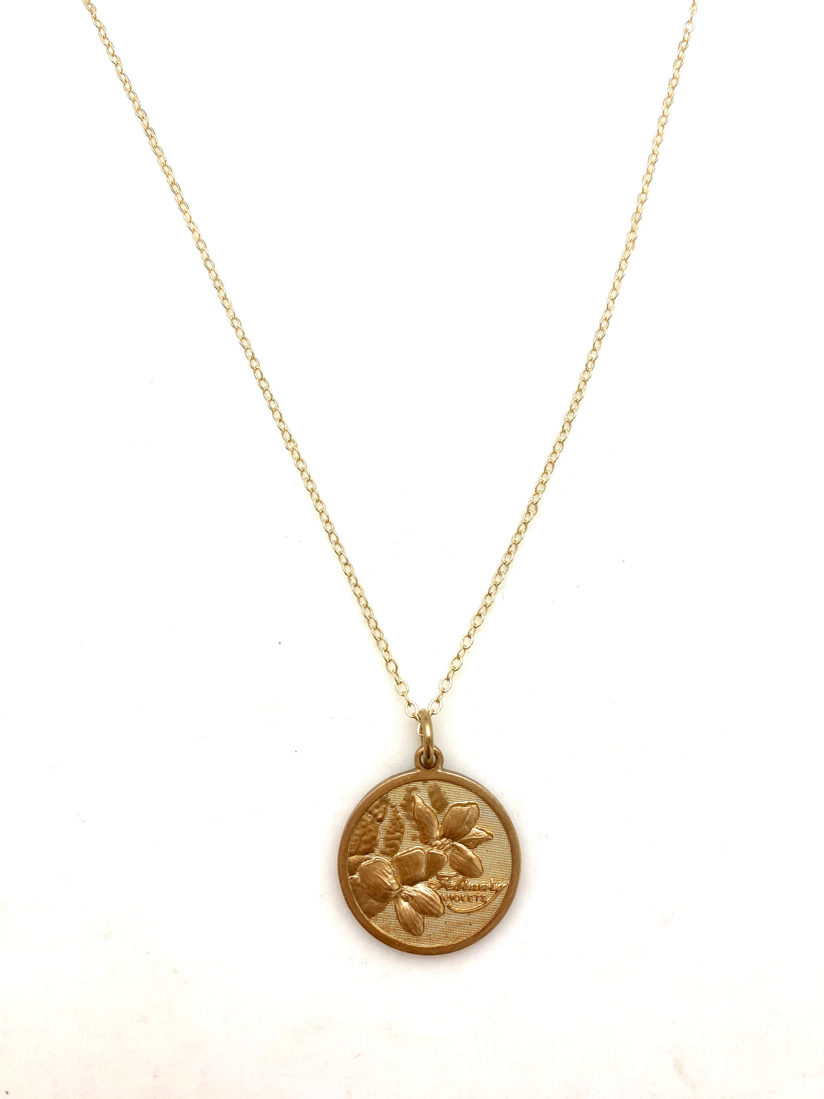 Gold embossed February violet birth month flower coin pendant necklace on a delicate gold chain on a white background