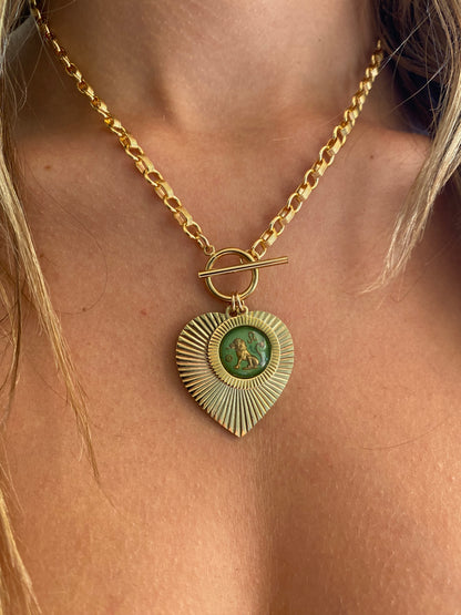Gold and green patina heart-shaped sunburst pendant necklace with a green vintage glass Leo lion intaglio cameo on a gold rolo chain with toggle clasp worn on a model close-up
