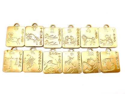 Complete set of 12 gold square zodiac pendant charms arranged in two rows on a white background featuring Aries ram, Taurus bull, Gemini twins, Cancer crab, Leo lion, Virgo maiden, Libra scales, Scorpio scorpion, Sagittarius archer, Capricorn sea goat, Aquarius water bearer, and Pisces fish with engraved zodiac names and symbols