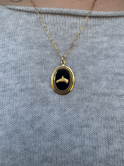 Gold necklace with a black pendant on a textured gray surface