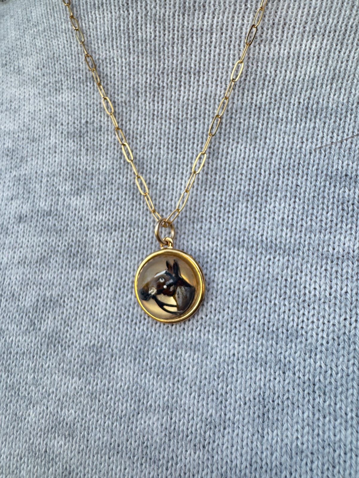 Gold necklace with a round pendant on a gray fabric background
