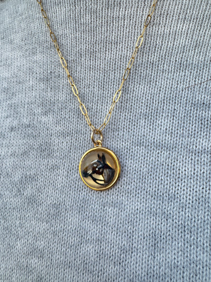 Gold necklace with a round pendant on a gray fabric background