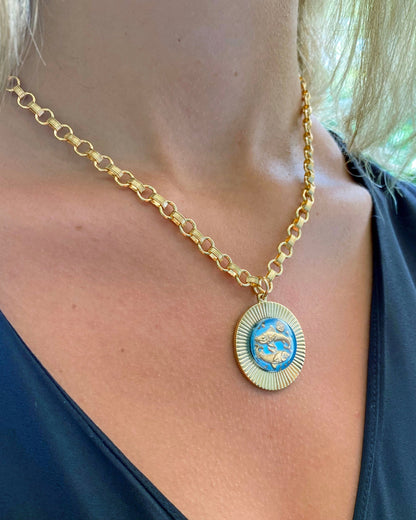 A person wearing a vintage large glass zodiac sign necklace on a gold fill heavy cable chain.