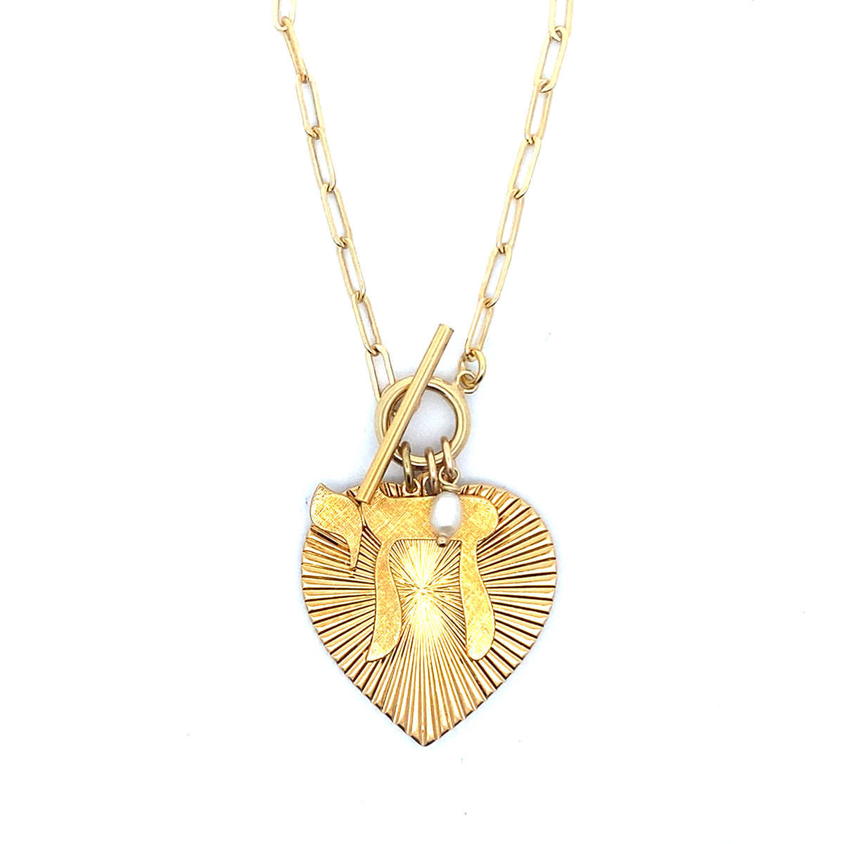 Gold ribbed heart-shaped pendant showing the back with starburst pattern and small pearl charm on a gold paperclip chain with toggle clasp against a white background