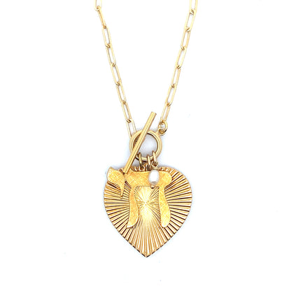Gold ribbed heart-shaped pendant showing the back with starburst pattern and small pearl charm on a gold paperclip chain with toggle clasp against a white background