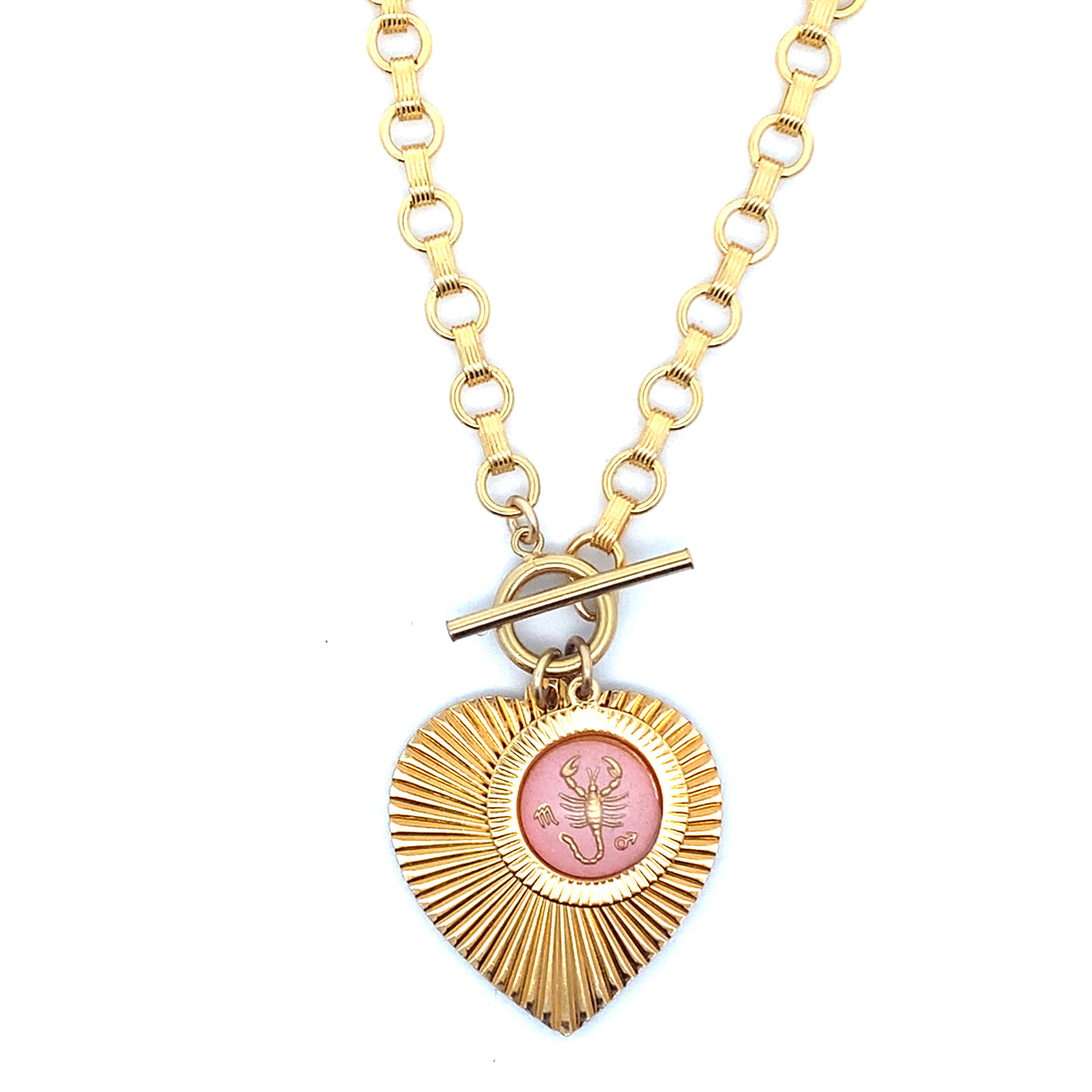 A gold ribbed heart-shaped pendant necklace with a Scorpio zodiac scorpion design in pink enamel center with toggle clasp closure on a gold round link chain against a white background