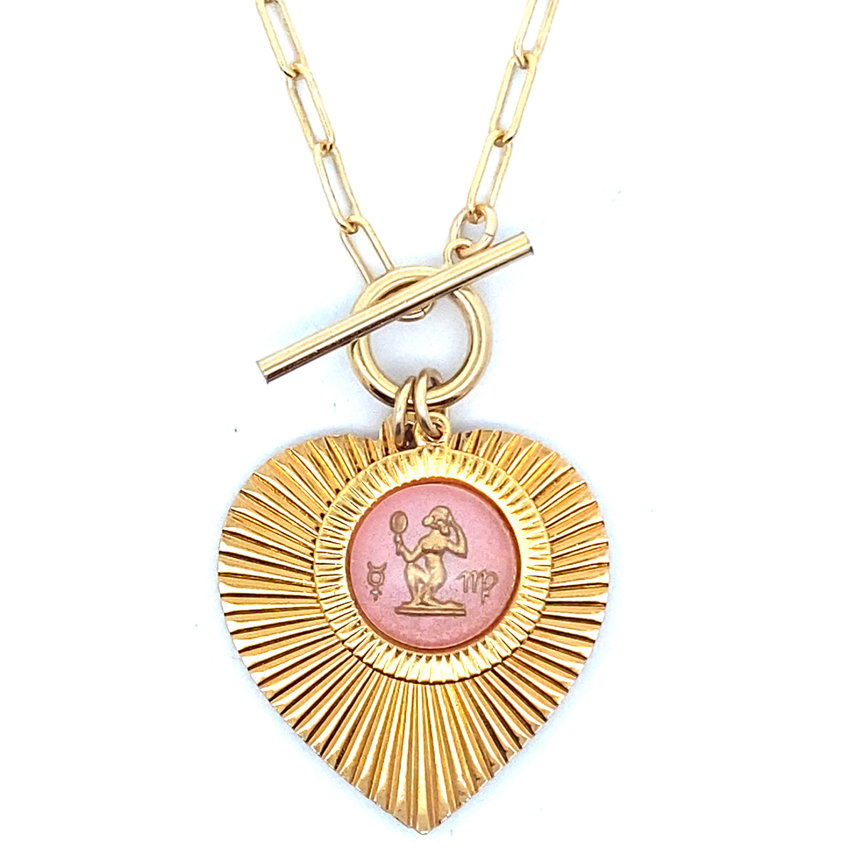 A gold ribbed heart-shaped pendant necklace with a Virgo zodiac maiden design in pink enamel center with toggle clasp closure on a gold paperclip chain against a white background