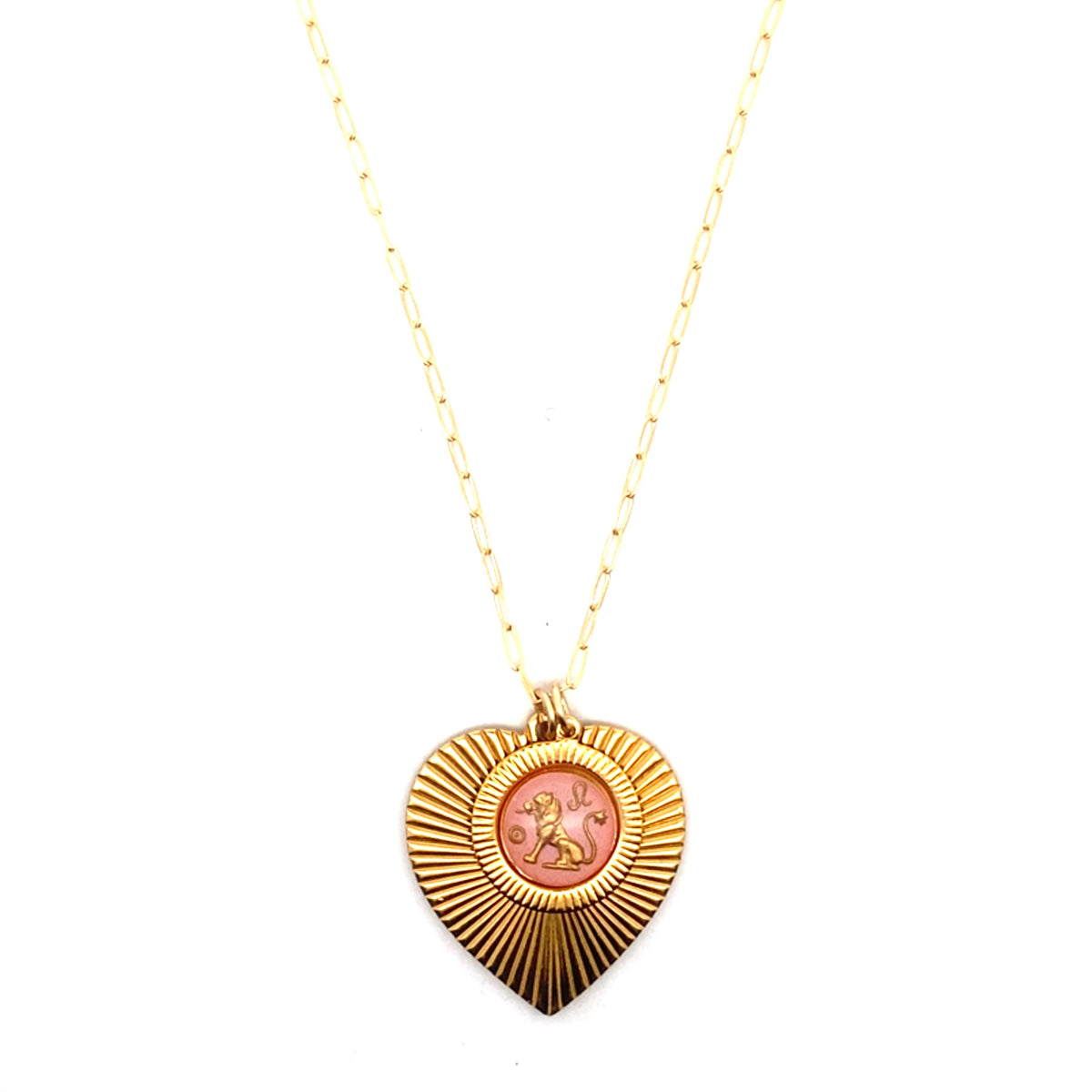 A gold ribbed heart-shaped pendant necklace with a Leo zodiac lion design in pink enamel center on a gold paperclip chain against a white background