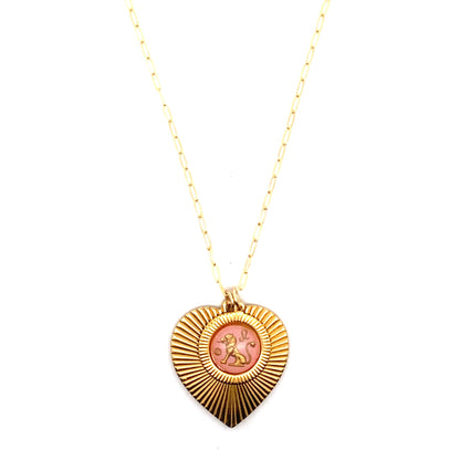 A gold ribbed heart-shaped pendant necklace with a Leo zodiac lion design in pink enamel center on a gold paperclip chain against a white background