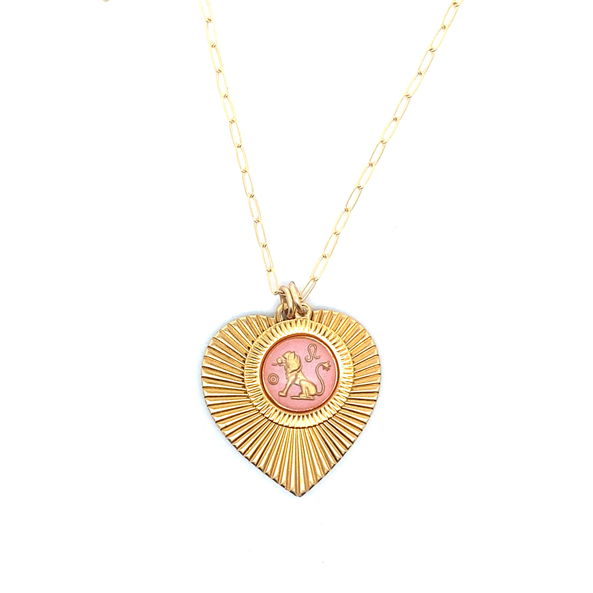 A gold ribbed heart-shaped pendant necklace with a Leo zodiac lion design in pink enamel center on a gold paperclip chain against a white background