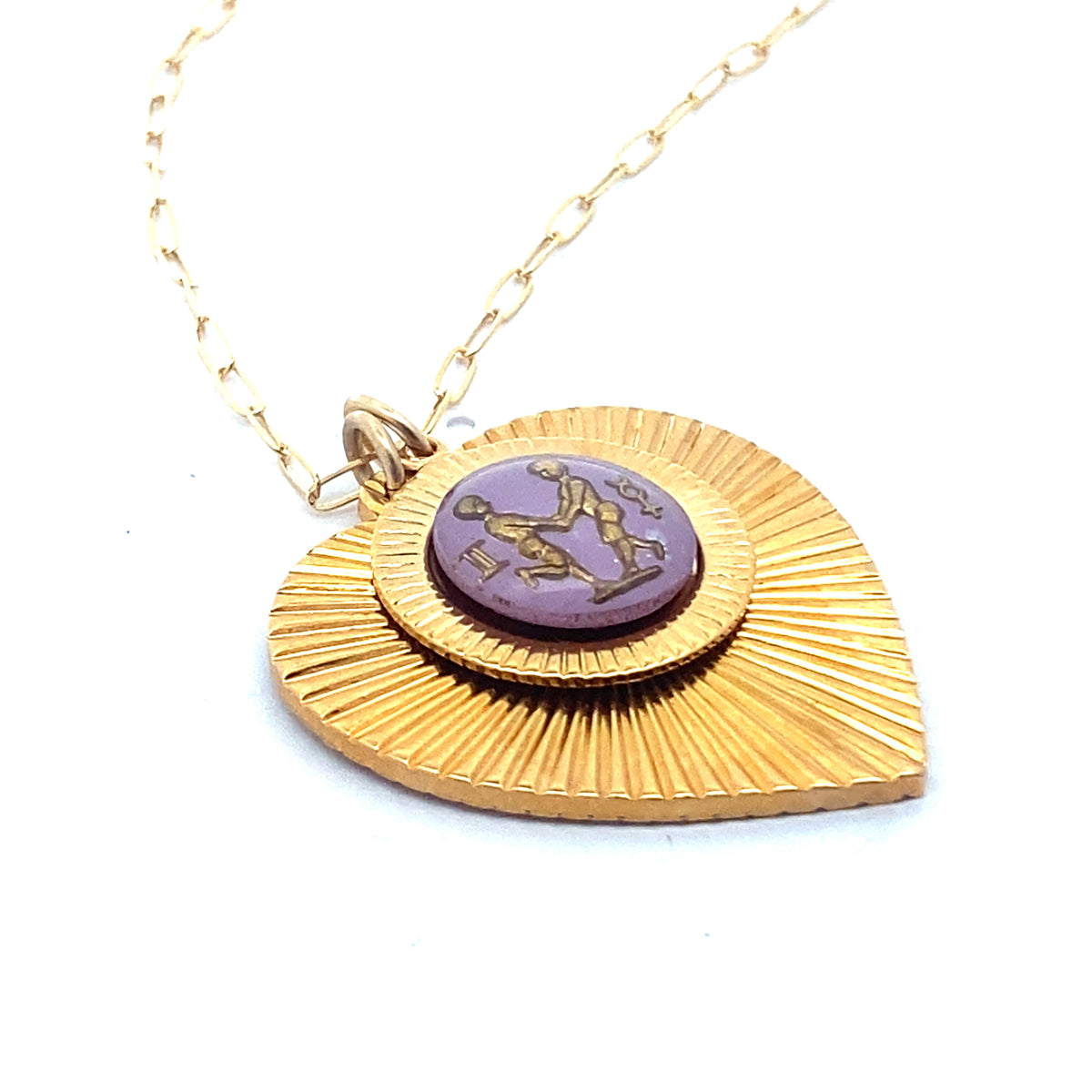 A gold ribbed heart-shaped pendant necklace with a Gemini zodiac sign in purple enamel center on a gold paperclip chain against a white background