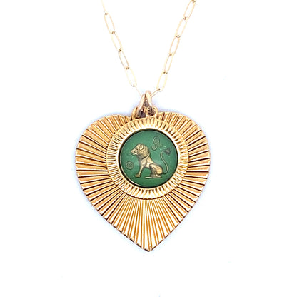 A gold ribbed heart-shaped pendant necklace with a Leo zodiac lion design in green enamel center on a gold paperclip chain against a white background