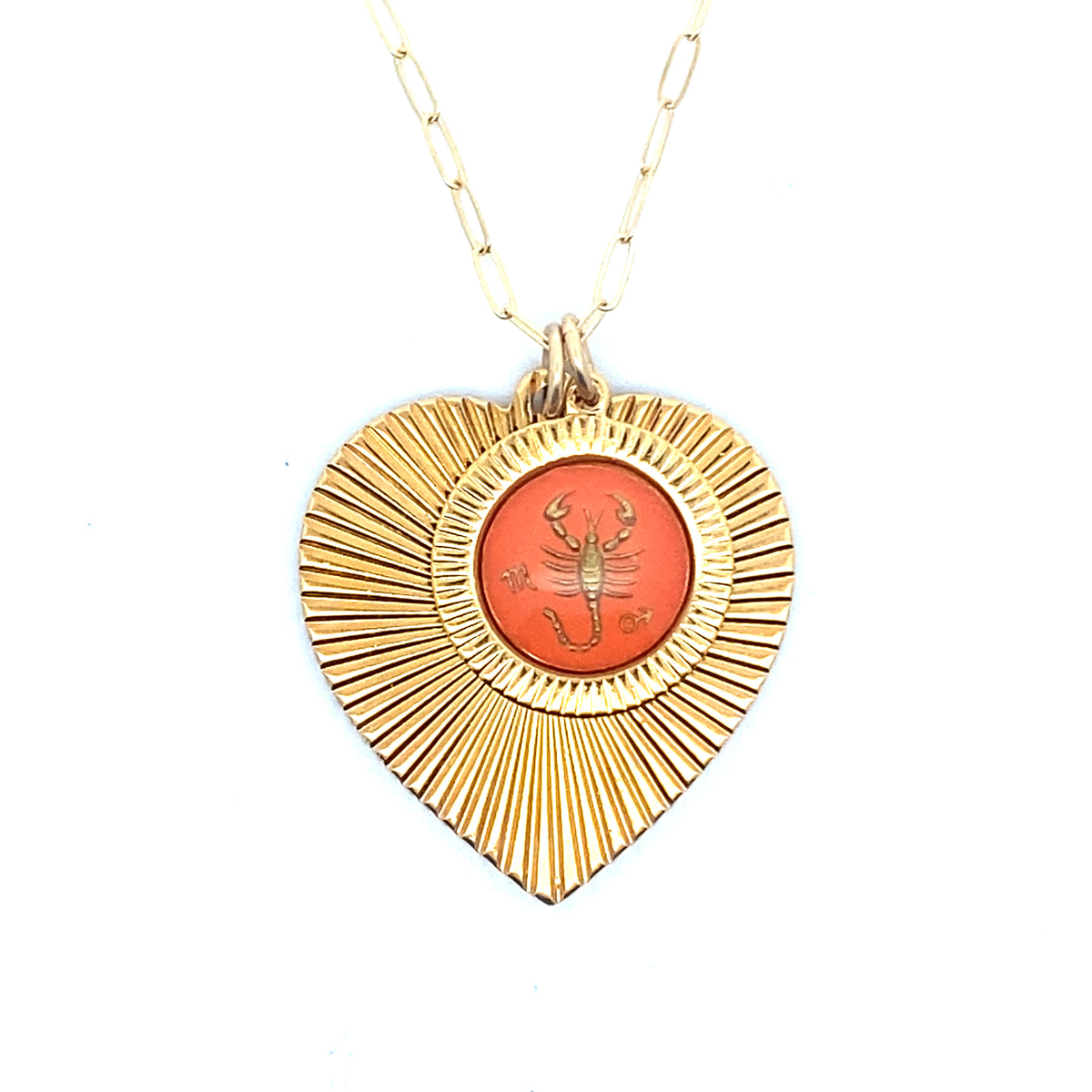 A gold ribbed heart-shaped pendant necklace with a Scorpio zodiac scorpion design in coral orange enamel center on a gold paperclip chain against a white background