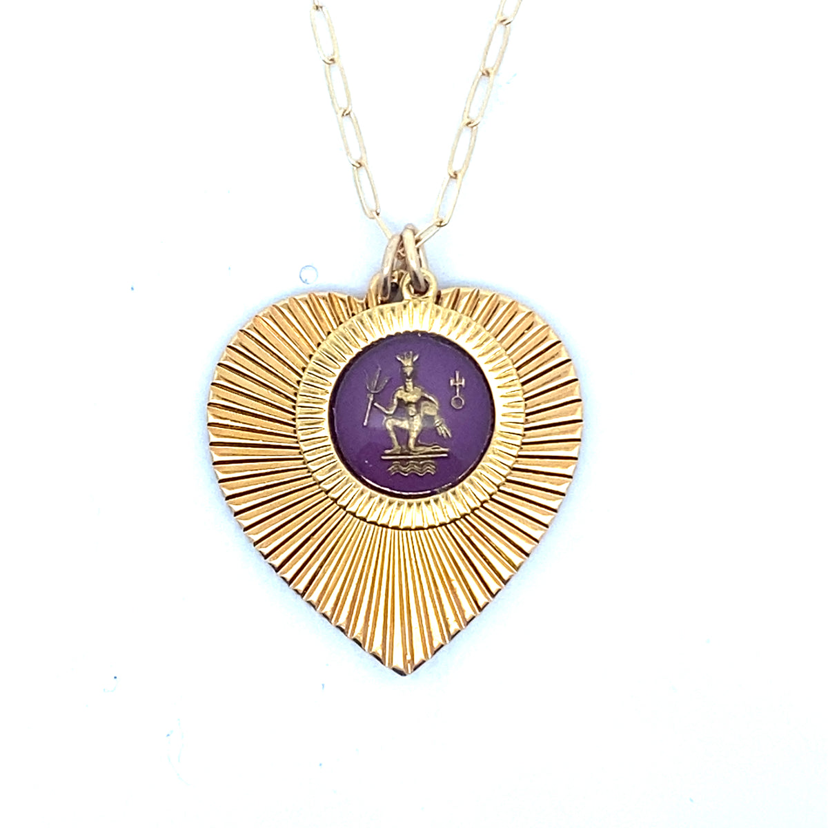 A gold ribbed heart-shaped pendant necklace with an Aquarius zodiac water bearer design in purple enamel center on a gold paperclip chain against a white background