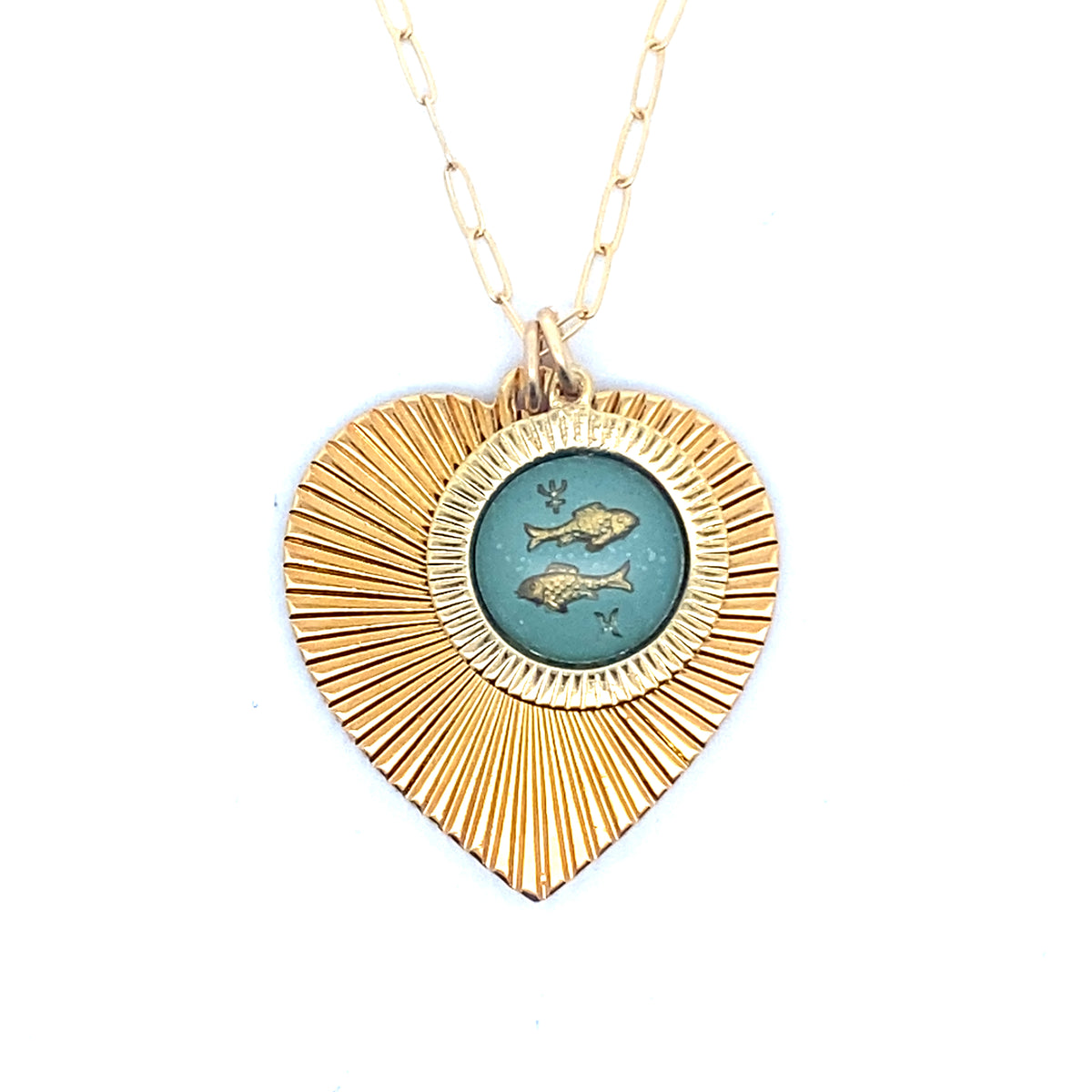 A gold ribbed heart-shaped pendant necklace with a Pisces zodiac fish design in teal enamel center on a gold paperclip chain against a white background