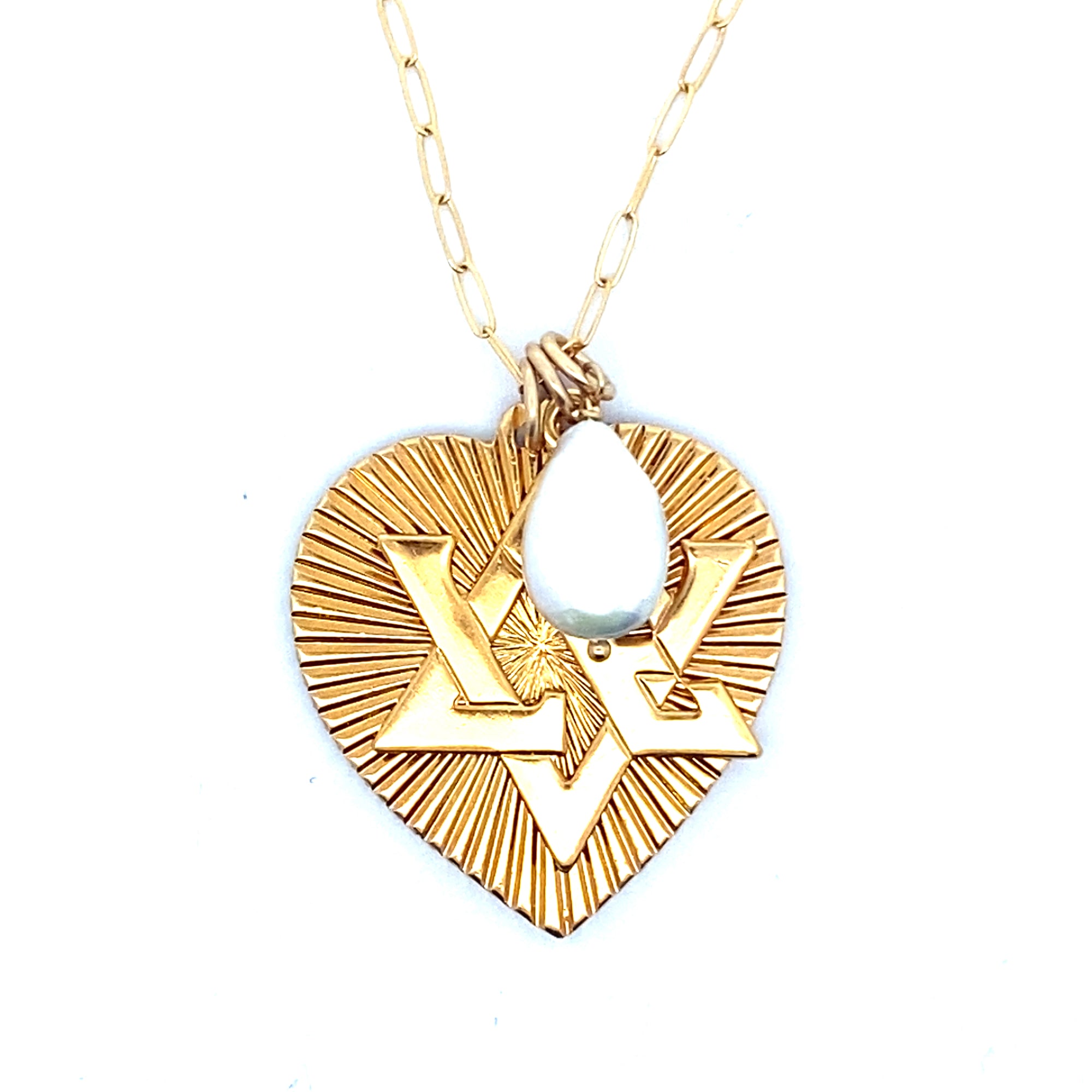 Close-up of a gold ribbed heart pendant with Star of David design and teardrop moonstone accent on a gold paperclip chain against a white background