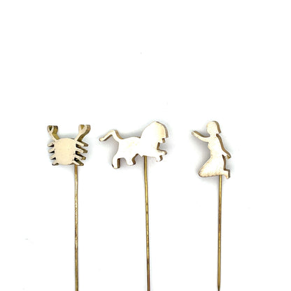 Three decorative sticks with crab, horse, and dancing woman shapes on a white background