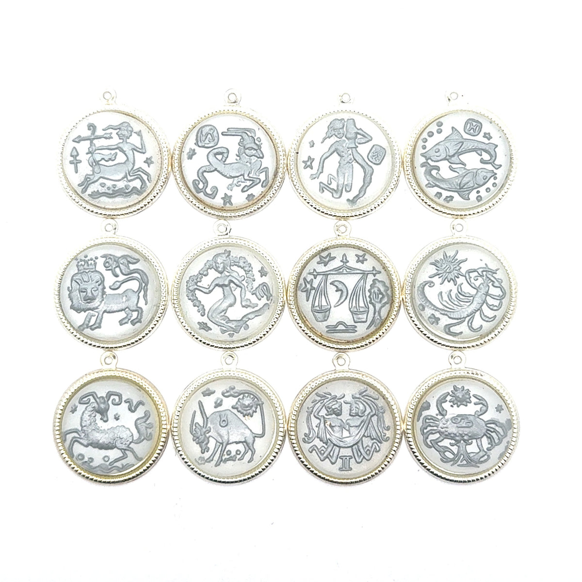 Collection of all twelve silver round zodiac coin charms arranged in a grid showing Sagittarius, Taurus, Aquarius, Pisces, Leo, Virgo, Libra, Scorpio, Capricorn, Aries, Gemini, and Cancer designs against a white background