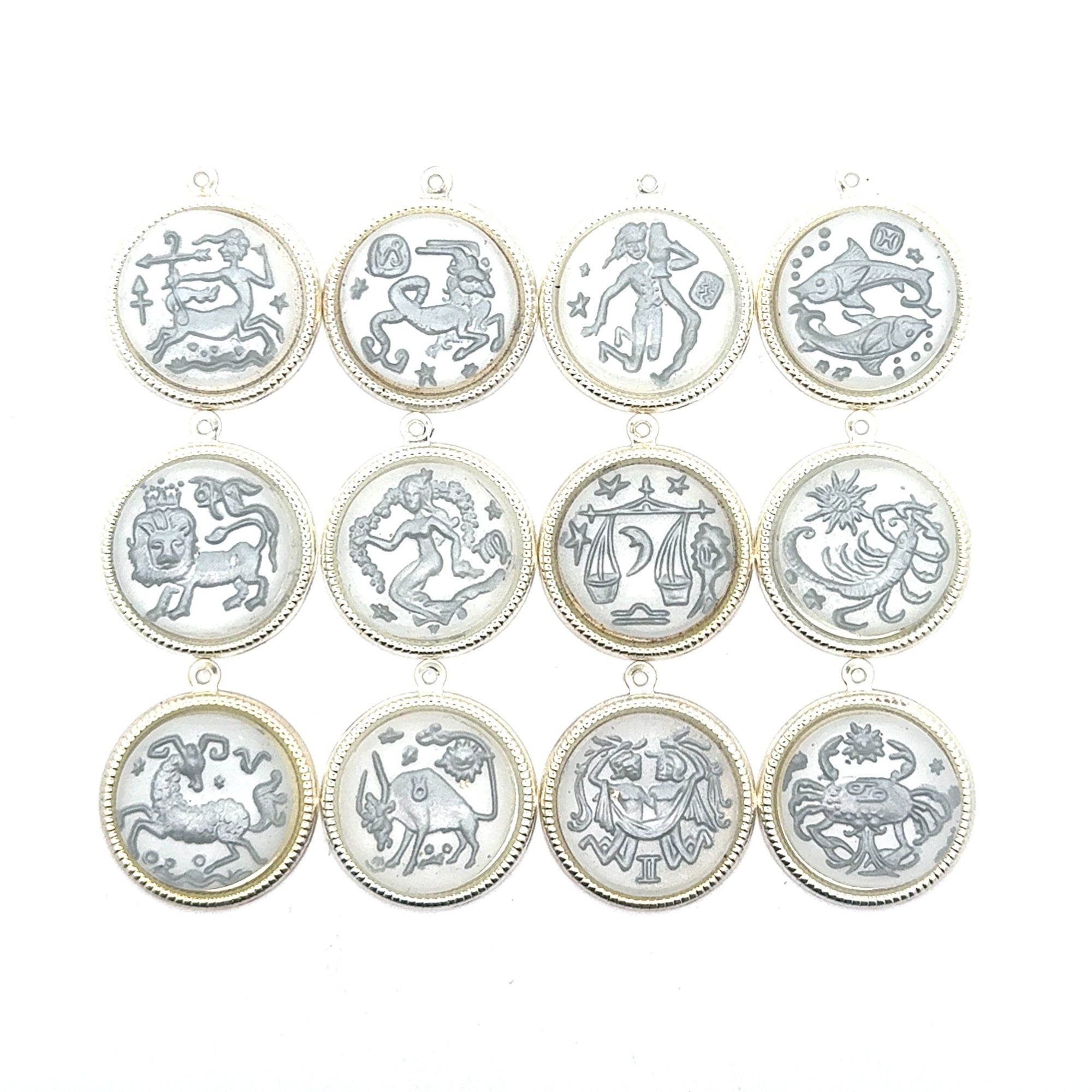 Collection of all twelve silver round zodiac coin charms arranged in a grid showing Sagittarius, Taurus, Aquarius, Pisces, Leo, Virgo, Libra, Scorpio, Capricorn, Aries, Gemini, and Cancer designs against a white background