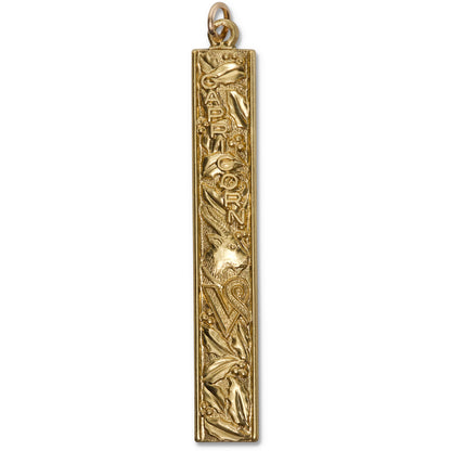 Gold vertical bar pendant charm with embossed Capricorn zodiac design featuring a sea-goat and decorative motifs on a white background