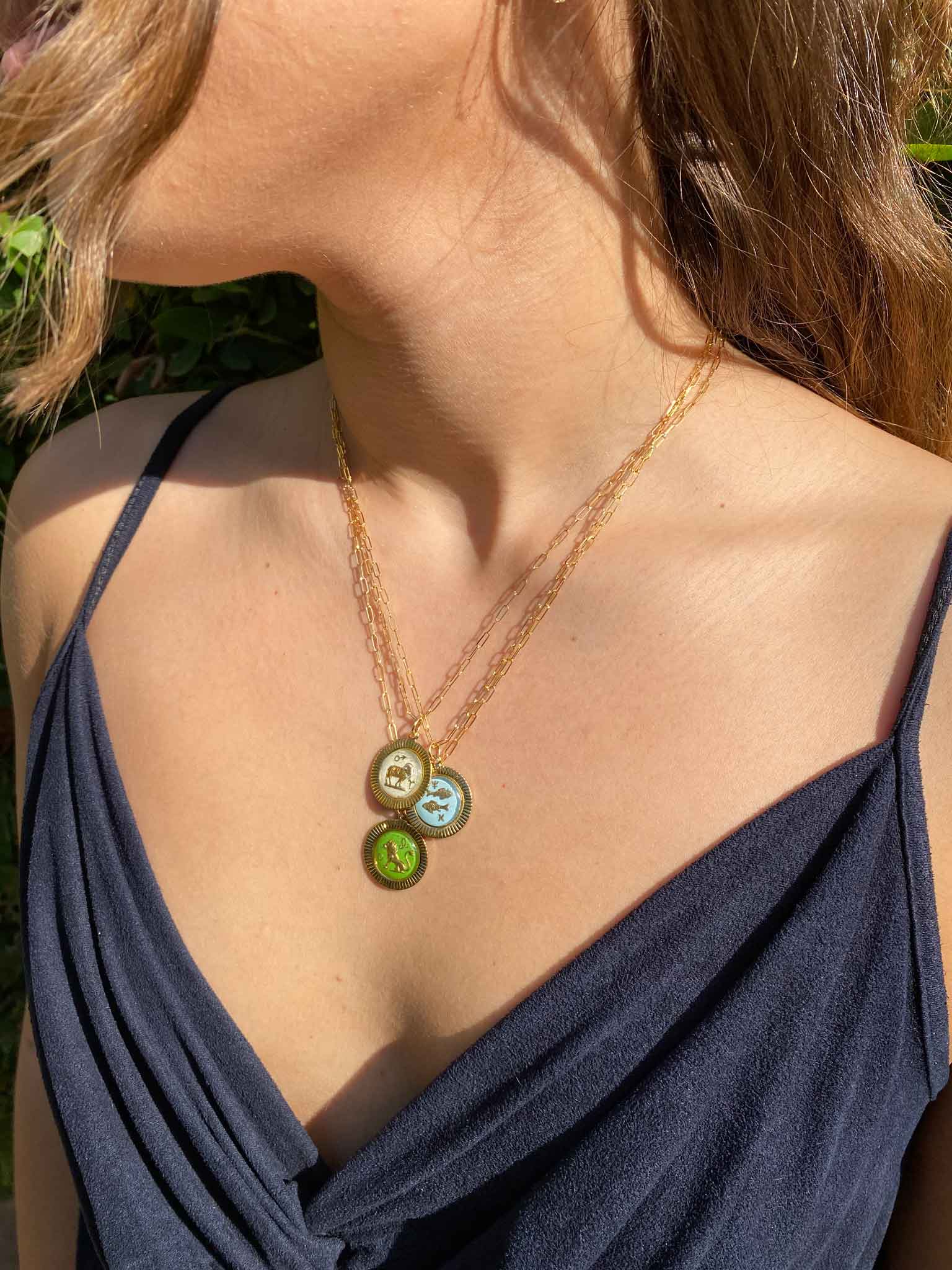 woman wearing a gold necklace with three small glass zodiac charms with frame 