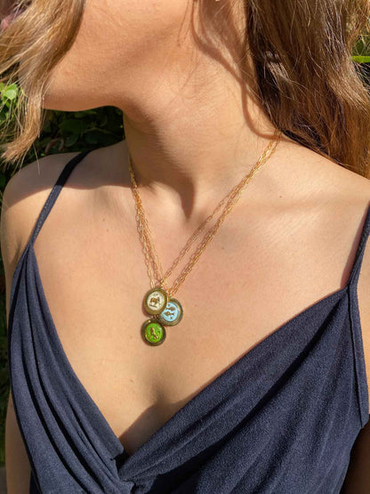 woman wearing a gold necklace with three small glass zodiac charms with frame 