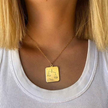 closeup of woman wearing a gold-plated necklace with a Libra vintage brass rectangle charm