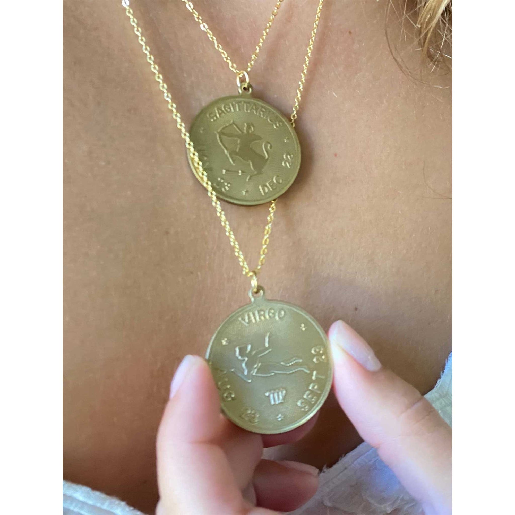 close up image of a virgo and Sagittarius vintage brass coin zodiac sign hung on a necklace 